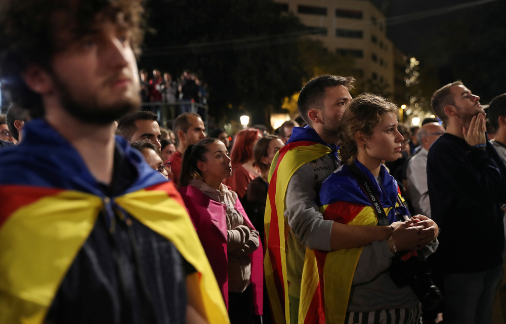 People react as they listen to Catalan president Carles Puigdemont during a gathering at Plaza Catalunya after voting ended for the banned independence referendum