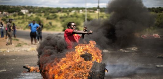 A demonstrator swings a burning tyre at a crossroad in Hebron during a protest for basic government services.
