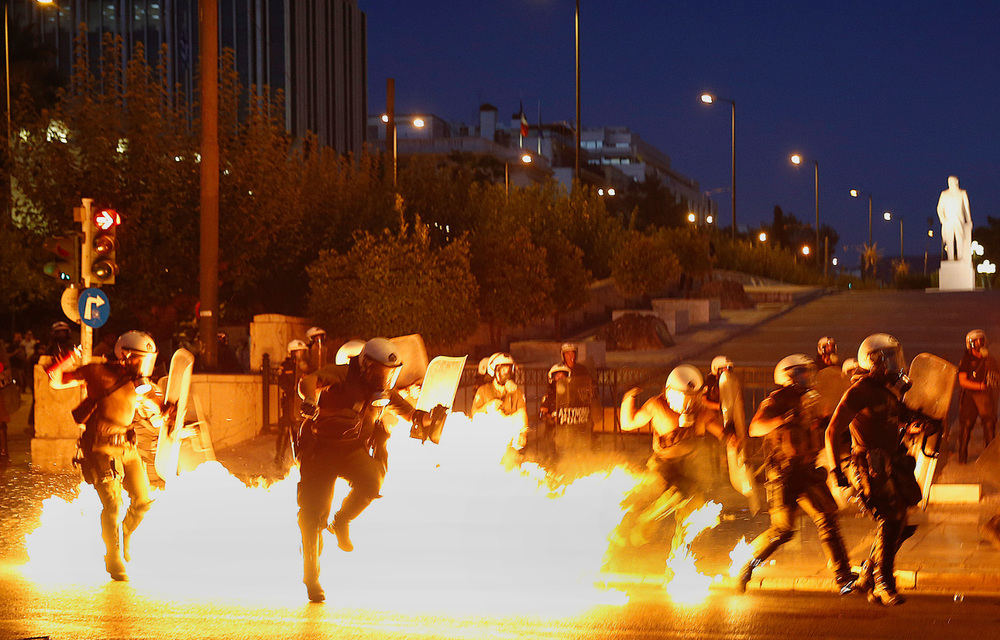 A Palestinian man walks past a fire in a street started to keep mosquitoes away from the shattered homes of Shujai’iya