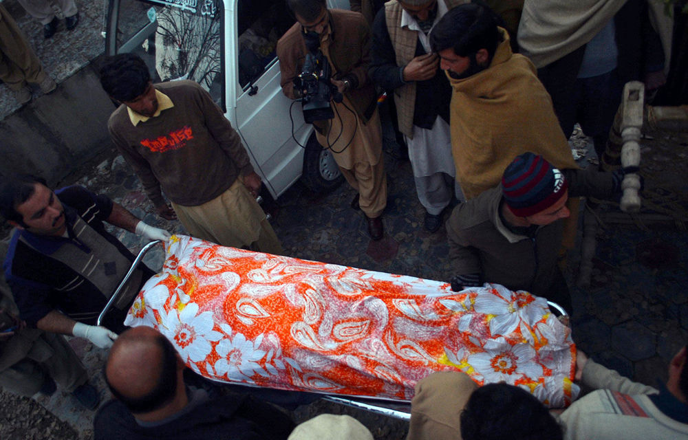 Pakistani volunteers transport the body of a charity worker following an attack by gunmen in Swabi on January 1 2013. Six women and a man were shot dead.