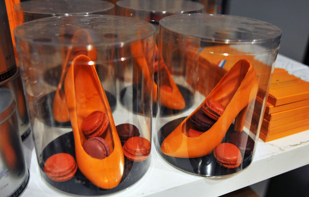 Orange shoe-shaped pastries and macaroons on sale in a shop in The Hague