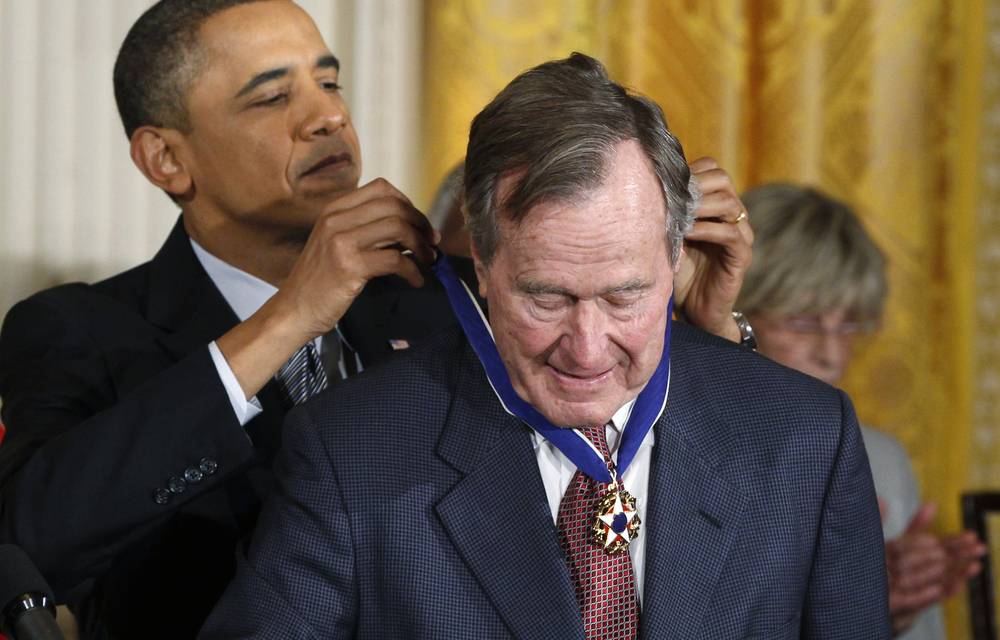 Former US president Barack Obama awards the Medal of Freedom to former US president George H.W. Bush during a ceremony to present the awards at the White House in February 2011.