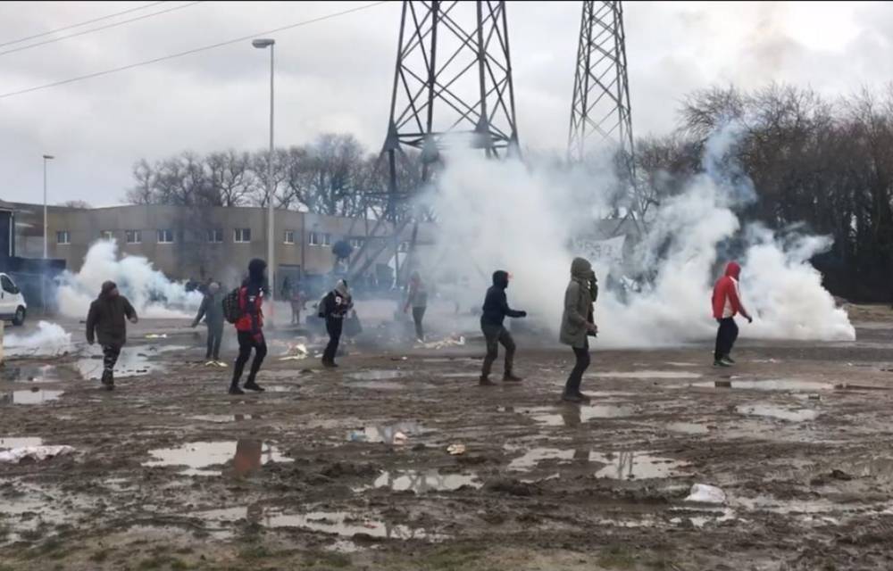 Refugees run and cover their faces after French police fire tear gas in Calais.