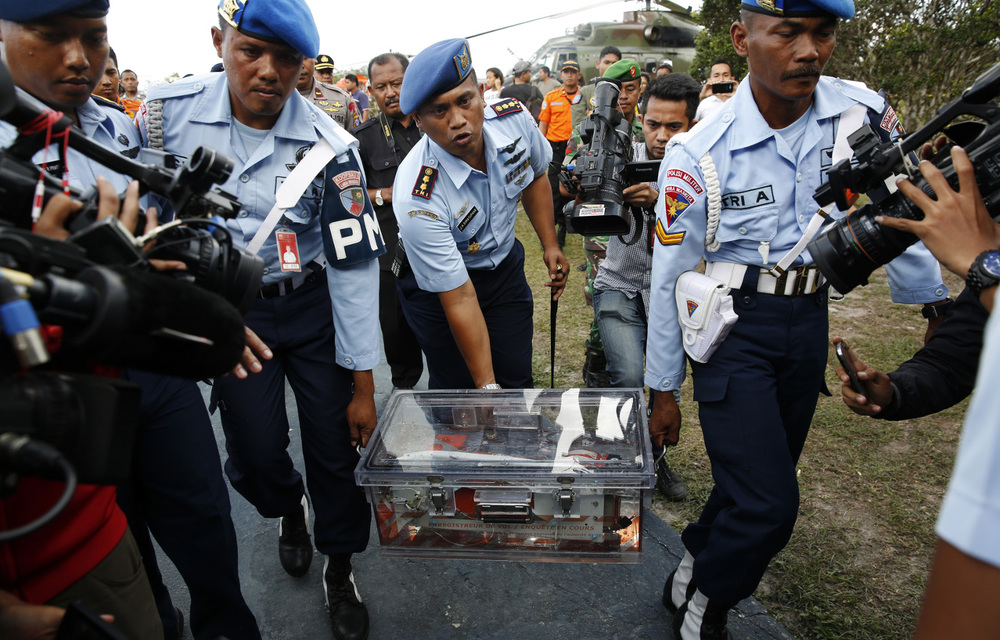 Military policemen carry the flight data recorder of AirAsia QZ8501 at the airbase in Pangkalan Bun