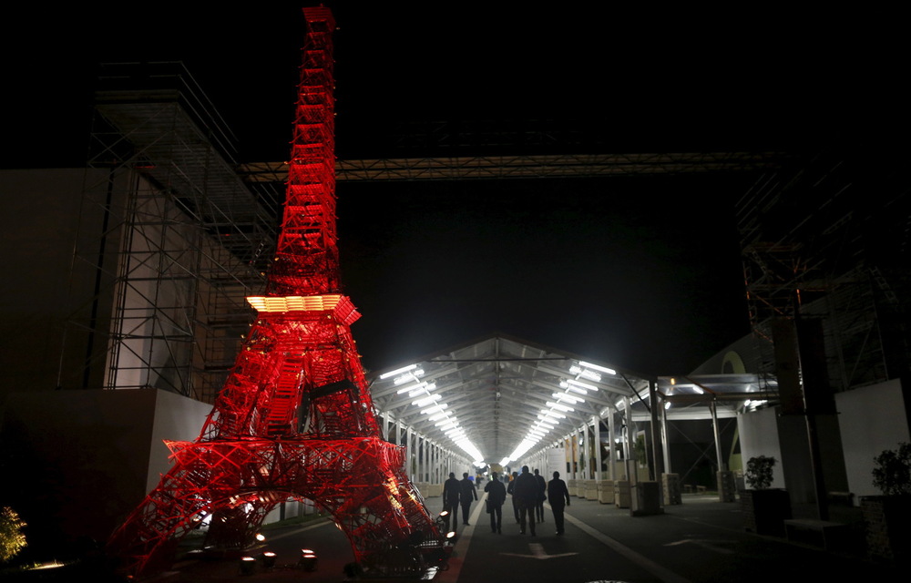 Participants walk near a replica Eiffel Tower constructed with bistro chairs during the World Climate Change Conference 2015