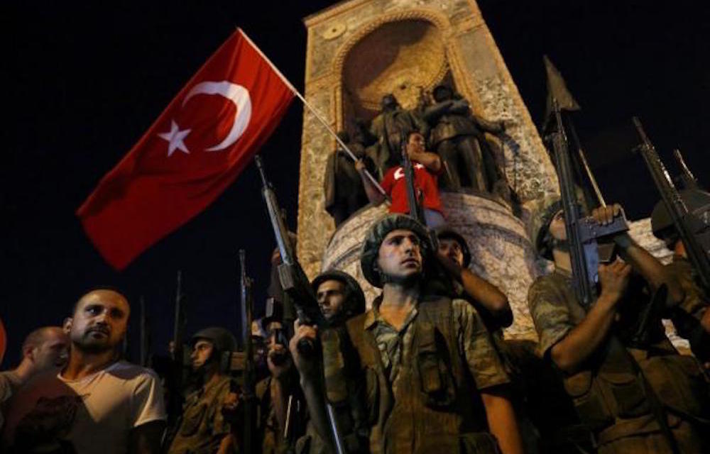 Turkish military stand guard near the the Taksim Square as people wave with Turkish flags in Istanbul.