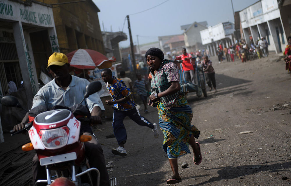 Residents run through the city following the sound of shell fire and gunshots in Goma