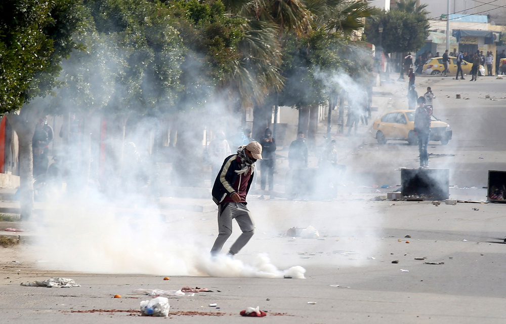 Tear gas is seen as protesters clash with riot police attempting to disperse the crowd during demonstrations