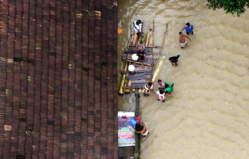 People wait for aid next to makeshift raft at a flooded area in the southern state of Kerala.