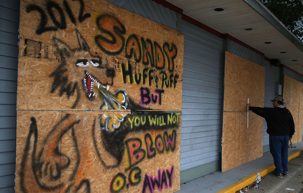 Ed Wicks secures plywood over the windows of a hair salon to protect from the high winds of approaching Hurricane Sandy in Ocean City