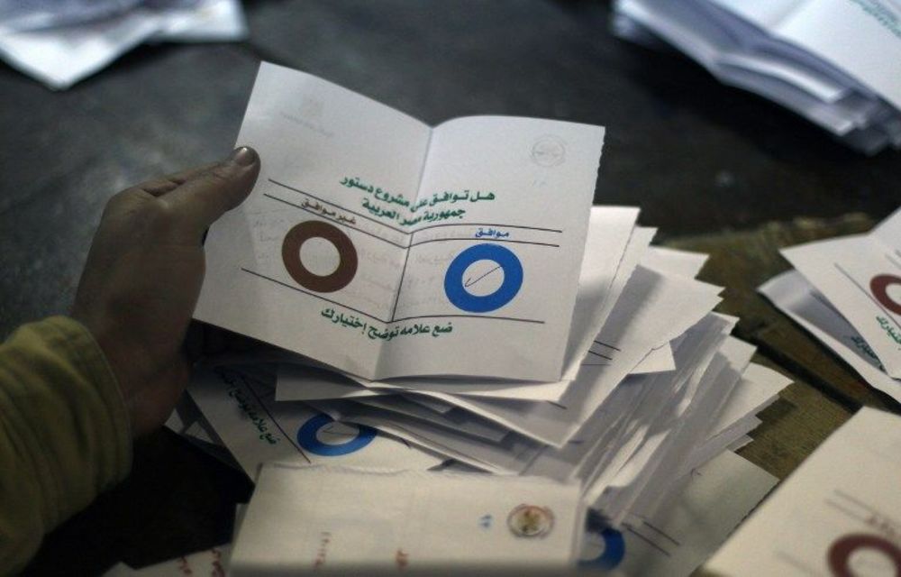 Polling station officials deposit ballots during the second round of a referendum on a new draft constitution in Egypt.