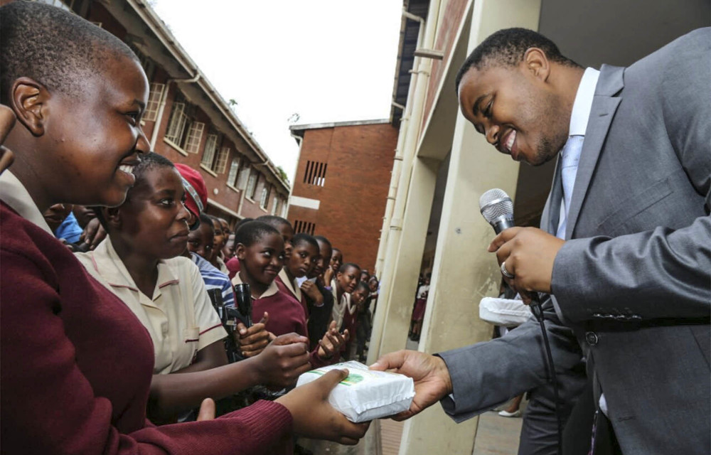 Education MEC Mthandeni Dlungwana hands sanitary towels to girls at Lamontville High School.