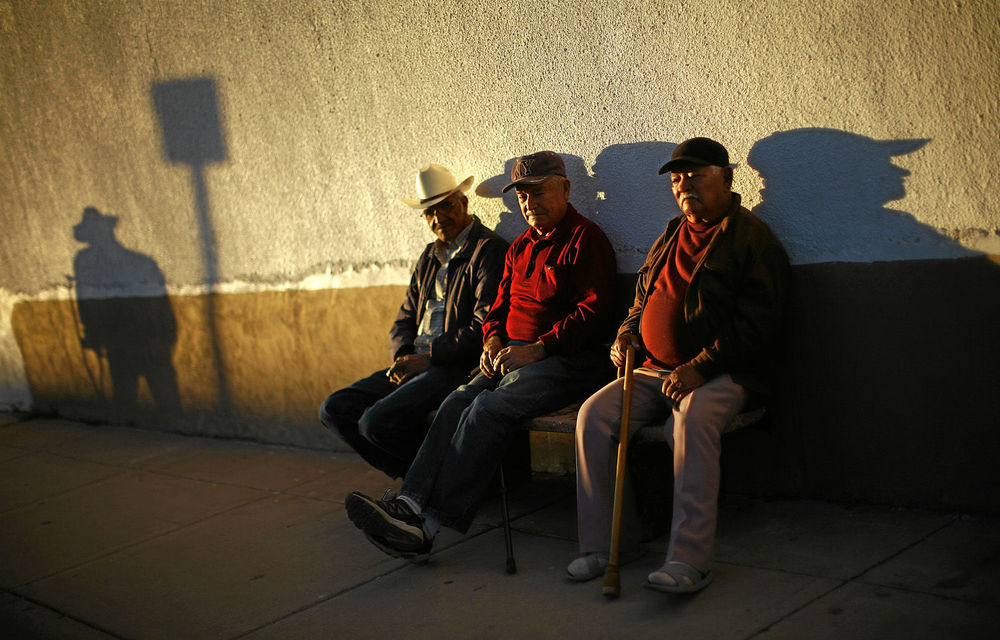 Three men sit near the fence separating the US and Mexico. Births and not illegal immigration account for the growth in the number of Hispanics in the US.