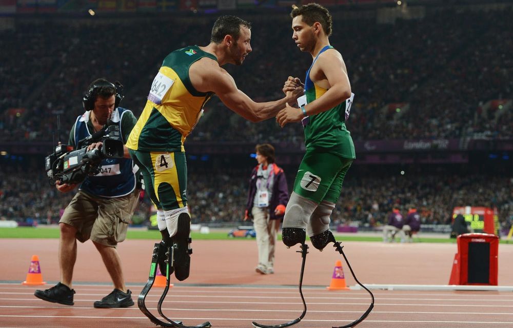 Alan Fonteles Cardoso Oliveira of Brazil is congratulated by Oscar Pistorius of South Africa after winning gold in the Men's 200m T44 Final.