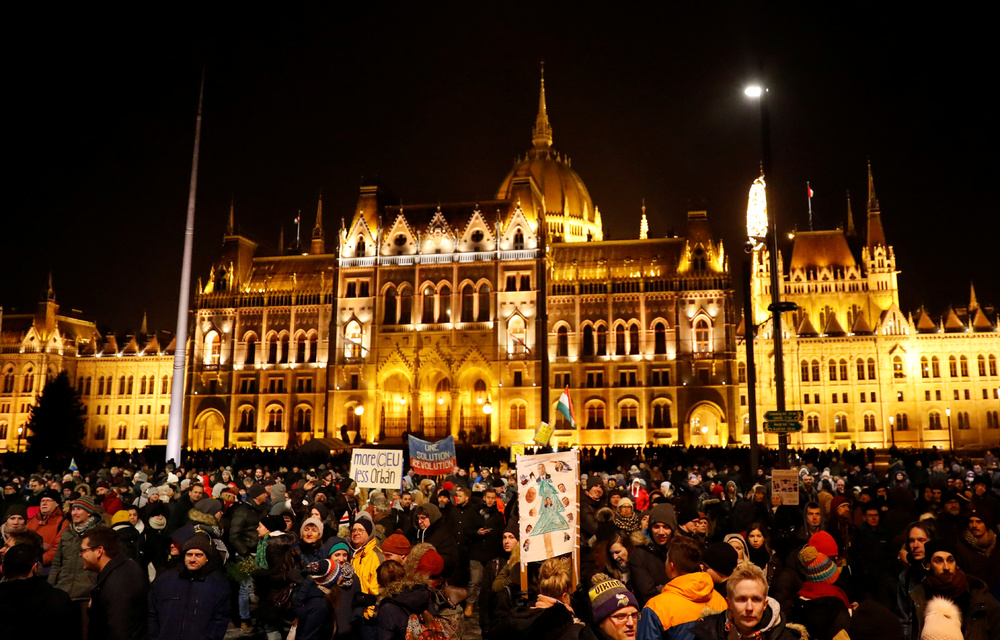 People stand in front of the Parliament building during a protest against a proposed new labour law