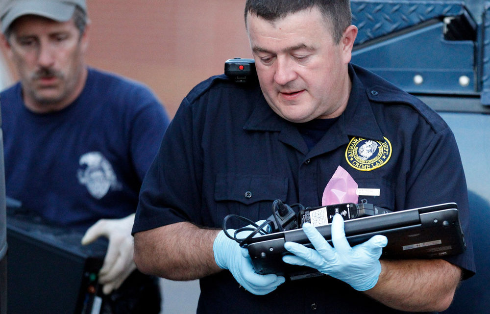 Investigators remove computer equipment as evidence from the apartment of alleged gunman James Holmes on July 21 2012 in Aurora