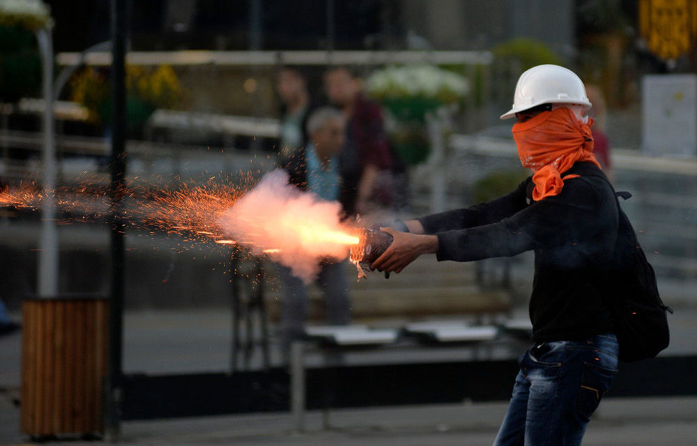 A protester fires firecrackers at riot polic  during a demonstration in Ankara blaming the ruling AK Party government for the Soma mining disaster.