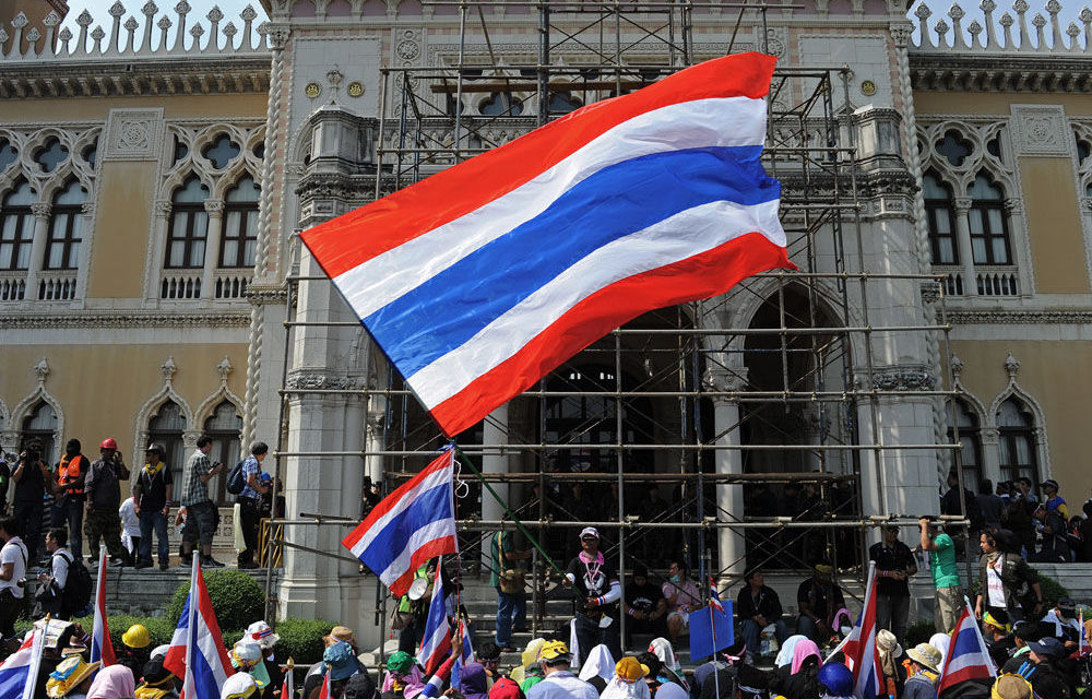 Thai anti-government protesters wave national flags after entering the Government House compound in Bangkok.