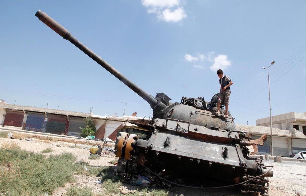 A Syrian child climbs a destroyed tank near Aleppo on August 4 2012.