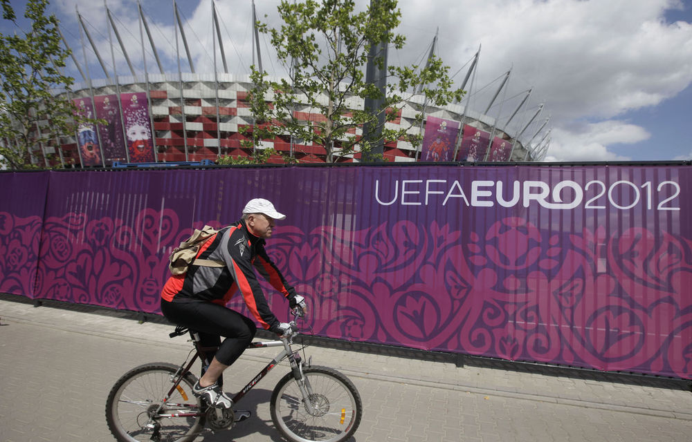 A cyclist passes the decorated fence surrounding Poland’s National Stadium in Warsaw