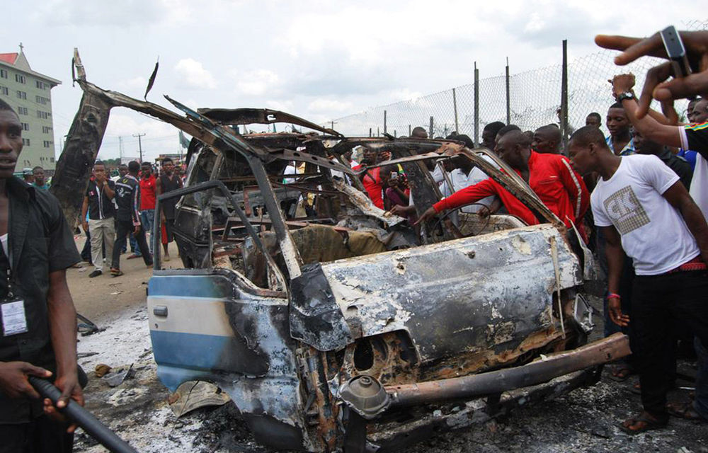 People look at a burnt-out bus