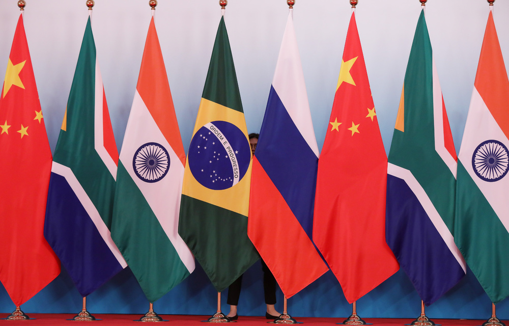 A staff worker stands behind the national flags of Brazil