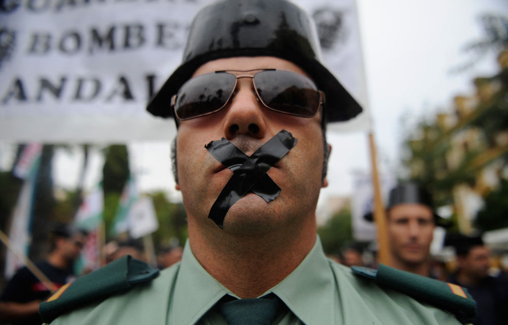 A Spanish civil guard with his mouth sealed with tape attends a demonstration of public service workers against government's spending cuts in Sevilla.