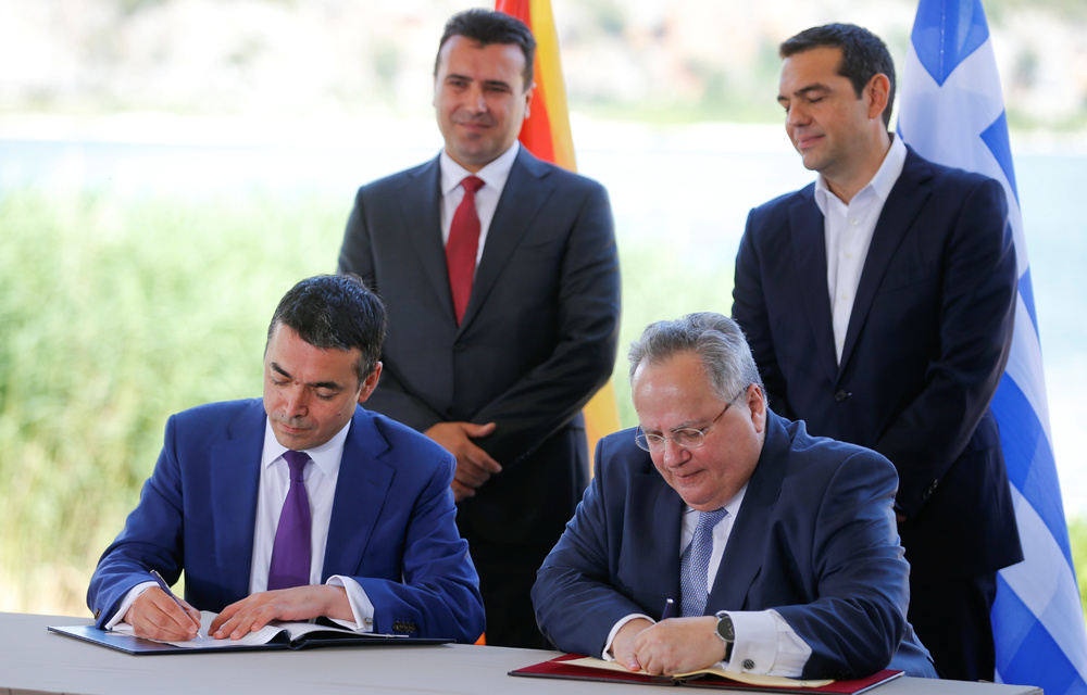 Greek Foreign Minister Nikos Kotzias and his Macedonian counterpart Nikola Dimitrov sign an accord to settle a long dispute over the former Yugoslav republic's name. Both Greece and Macedonia's prime ministers look on.