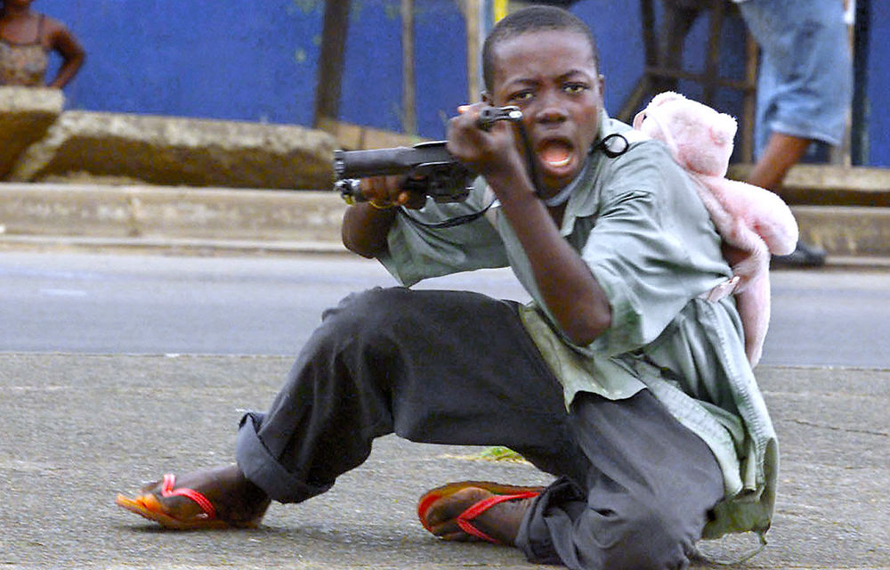 A child soldier wearing a teddy bear backpack in Monrovia