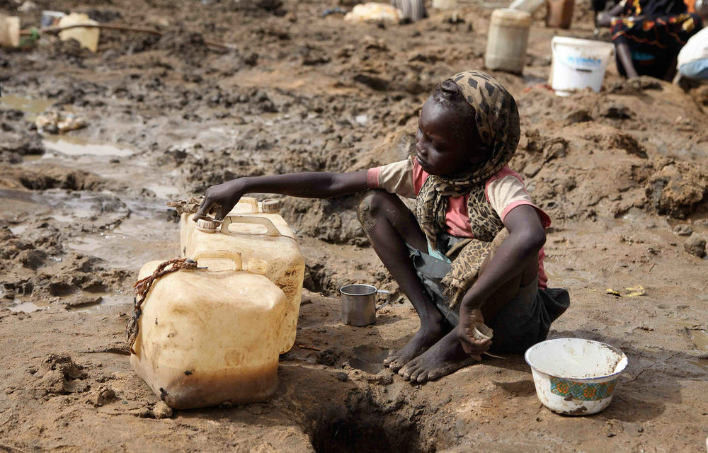 A young girl fetches murky water from a hole dug near a dried well in Jamam