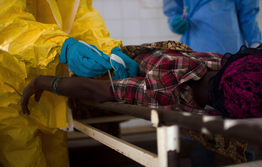 Medical staff take a blood sample from a suspected Ebola patient at the government hospital in Kenema