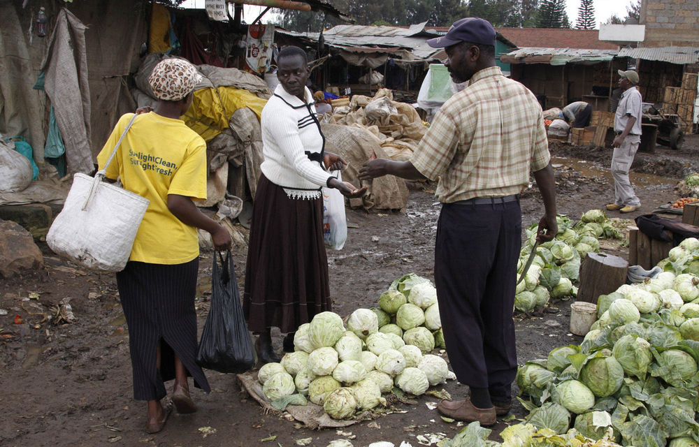 A woman buys cabbages in a vegetable market in the Kibera slum in Nairobi