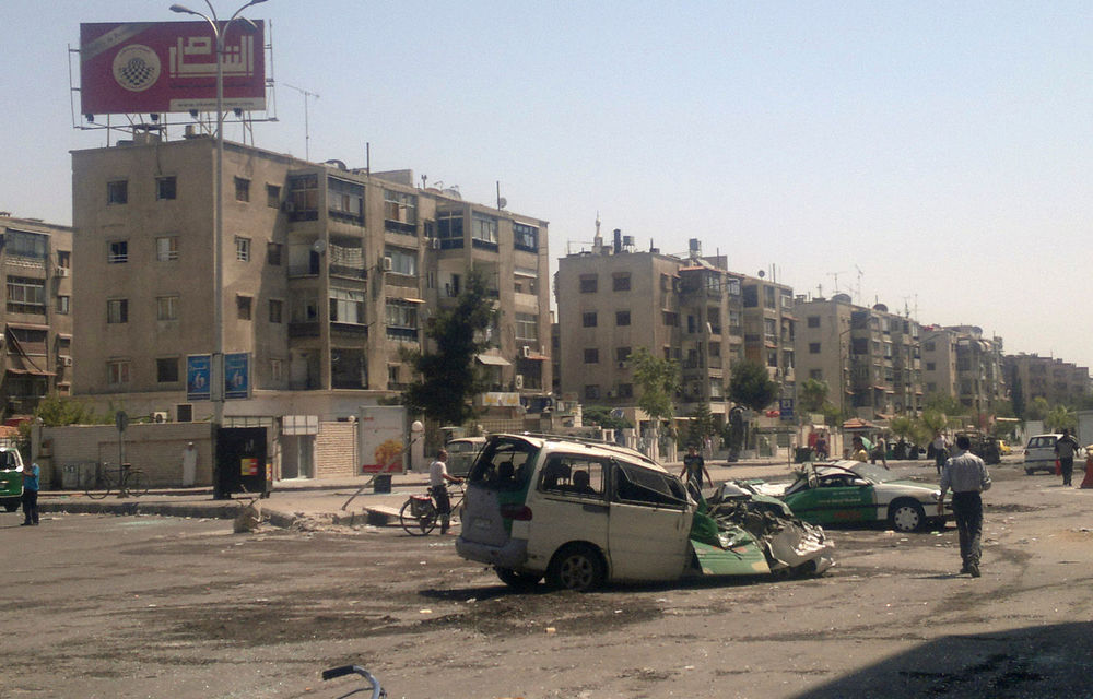 Syrians walk past destroyed vehicles after fighting between rebels and troops in the Yarmouk camp for Palestinian refugees in south Damascus on July 21.