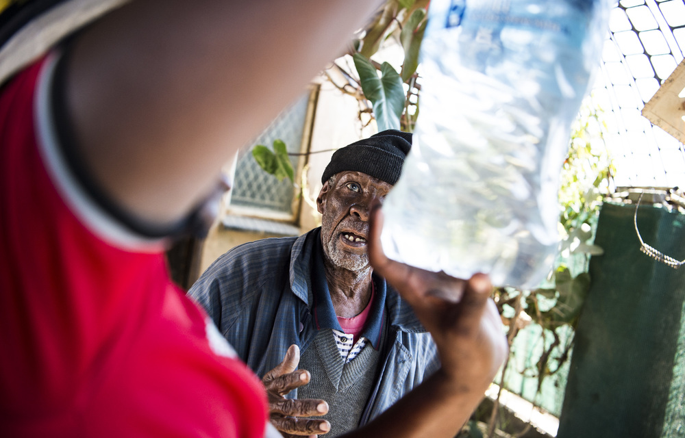 On the bottle: The 82-year-old James Mutle has to pay youngsters to chase after trucks that deliver drinking water otherwise he and others have to buy bottled water.