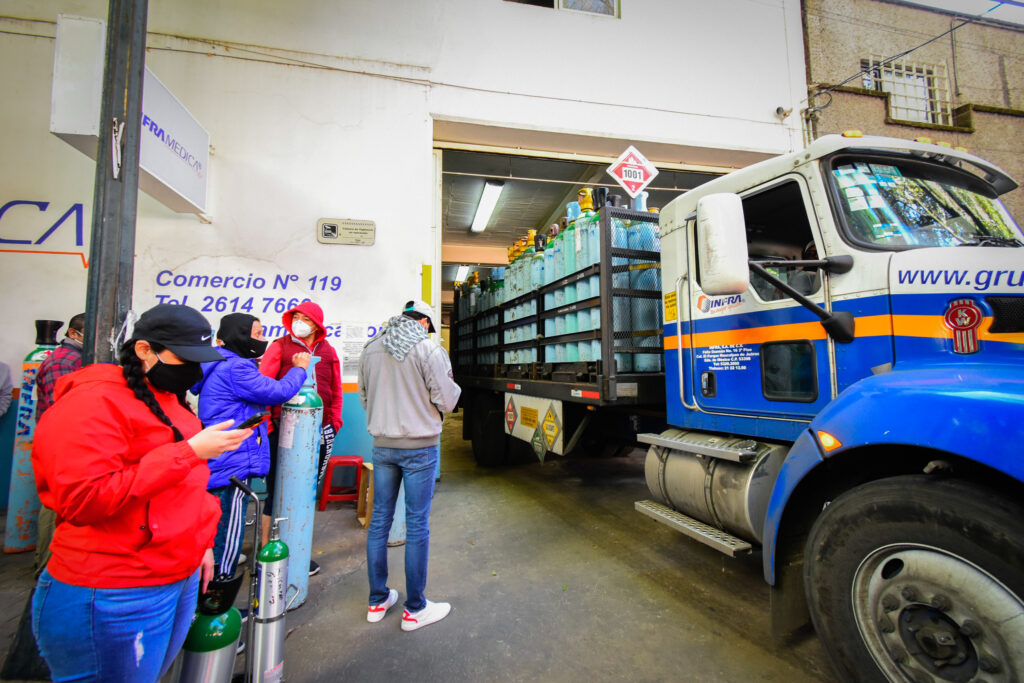 People Wearing Face Masks Wait In A Line To Refill Their