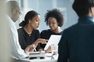 Group Of Co Workers Standing Around Desk And Having Meeting