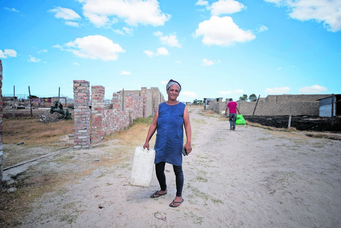 Faeza Meyer, African Water Commons Collective Founder, Collecting Fresh Water For Her Family From A Pipe Left Out At A Neighbour’s Plot In Silvertown Near Malmesbury. Tuesday 16 January 2024. (photo: David Harrison)