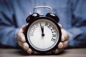 Businessman Holding Black Alarm Clock With Clockwise Countdown From Work To Retirement.